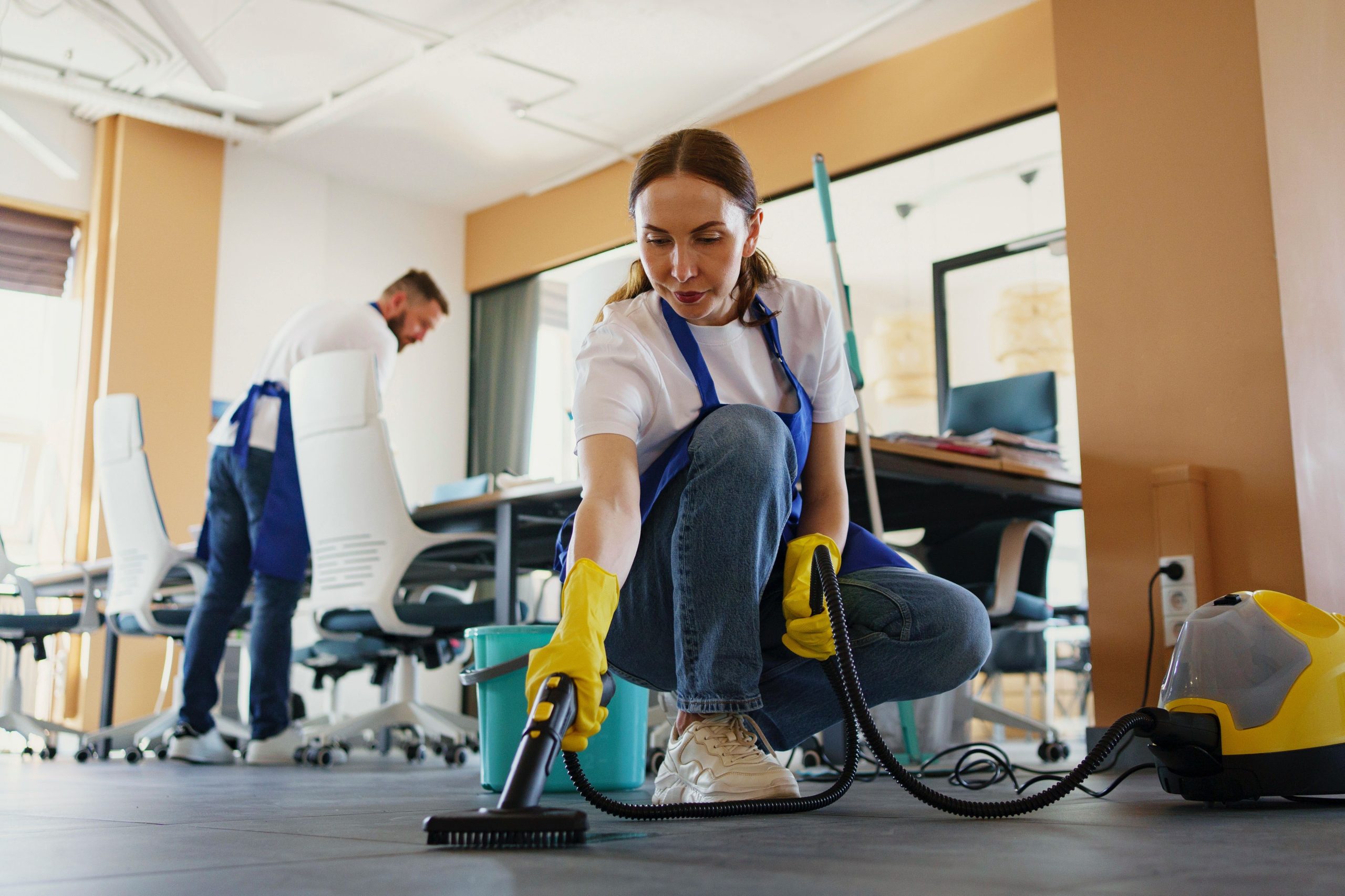 A man and woman providing commercial janitorial services in Miami Beach, cleaning office floors with professional equipment.